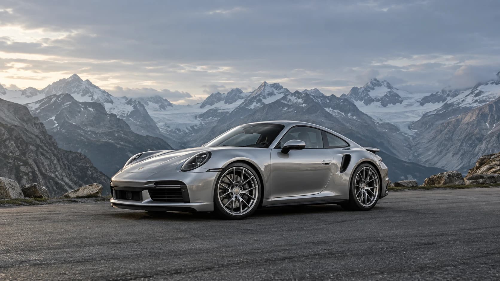 Silver performance coupe with forged wheels on a sweeping alpine pass
